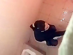 Asian woman spied over the toilet wall taking a pee